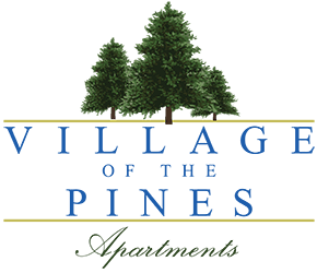 A logo for "Village of the Pines Apartments" featuring two trees.
